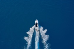 luxury motor boat. Aerial view of a boat in motion on blue water. Top view of a white boat sailing in the blue sea. Drone view of a boat sailing at high speed.