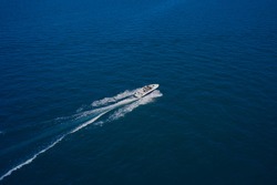 Top view of a white boat sailing in the blue sea. A boat with a motor on blue water. Aerial view luxury motor boat. Top view of the boat.