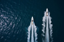 Speed boats movement on the water. Speed boats on dark blue water aerial view. Two speed boats moving fast on dark blue water.. Large white boat driving on dark water.