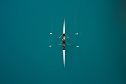 White rowing boat in motion with two women, top view. Top view of the rowing race. Aerial view of rowing. Rowing on the water aerial view.