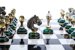 Malachite stone green chess pieces with nacreous elements as rivals, in centre on marble chessboard. Close up game concept competition, Classic Tournament.