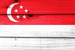 Singapore flag painted on old wood plank background. Brushed natural light knotted wooden board texture. Wooden texture background flag of Singapore