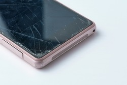 worn pink smartphone with cracked and scratched screen on white background