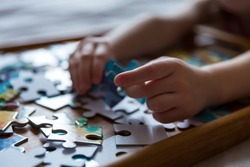 Children's hands collect puzzles. An educational game for a kid. Close-up