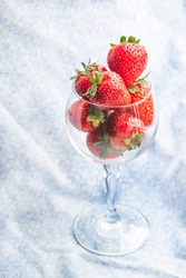 Close up picture of glass with strawberries on blue background. Copy space concept with flat lay composition. Summer period of time with fresh berries. Wallpaper with fruits in sheer glass.