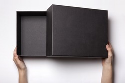 A female(woman, girl) two hands hold and open the empty(blank) black box isolated white, top view at the studio.