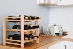 Wooden wine supply with bottles on table in modern kitchen.
