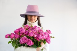 girl in a hat and a bouquet of roses in her hands