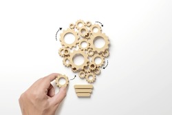 Business process and workflow automation with flowchart. Hand holding wooden cog flowing process management lightbulb shape on white background