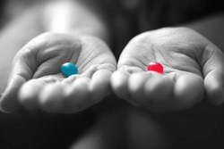 A girl holding a red and a blue jelly bean in her palms.