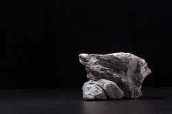 Luxury natural stone podium for showing packaging and product on black background, copy space.