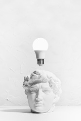Brainstorming concept with glow light bulb over head of white antique statue David in intense thinking and creativity process, vertical, copy space. College and school education background.