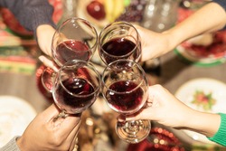 Friends with wine glasses in the restaurant for christmas. Cheers! Hands holding wine glass. Celebration, christmas and drink concept.