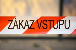 Signal red and white ribbon with forbids entrance to place in city on Czech language. Warning sign on blurred background closeup