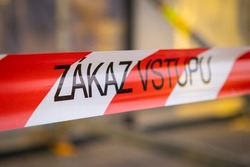 Signal red and white ribbon with Czech inscription Zakaz vstupu forbids entrance to place in city. Warning sign on blurred background closeup