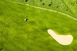 Golf course with sand bunker and green grass, aerial view.