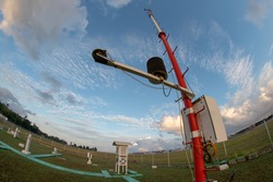 An Automatic Weather Station at Bali Meteorology Station with a landscape of Meteorological garden in the morning. Under the blue sky with partly grey cumulus and cirrus clouds. Shoot on fisheye lens