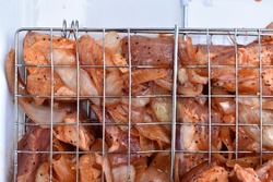 Raw pork meat in a barbecue net with spices
