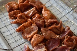 Raw pork meat in a barbecue net with spices