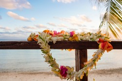 A beautiful lei of flowers rests on a the railing of a wooden deck overlooking a lagoon in French Polynesia in the South Pacific