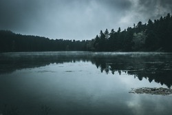 View of a dark moody sky at Golcuk Nature Park in Bolu / Turkey. The lake is surrounded by pine, fir, beech, hornbeam and mixed types of trees.