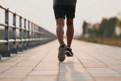Runner feet running on road closeup on shoe. MAN fitness sunrise jog workout welness concept.