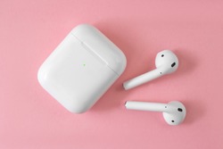 white wireless headphones on pink background. female headphones. copy space