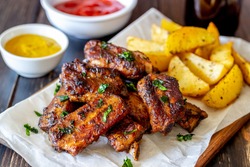 Pork ribs with potatoes on a wooden background. Barbecue. Grill. American cuisine. Recipe
