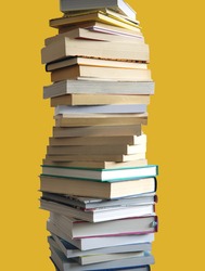 A tall stack of many books piled high, isolated on yellow