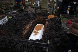 Grieving relatives bury the white coffin in the pit, throwing clay on the coffin