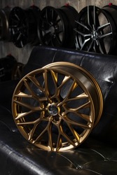 Stylish new shiny gold car rim on black leather sofa in car rims showroom