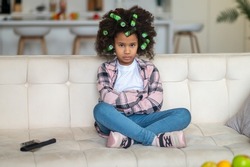 Girl in curlers sitting on couch looking at camera