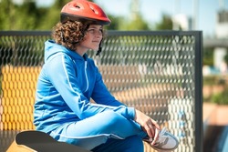 Calm dreamy adolescent skateboarder sitting alone outdoors