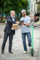 Businessman receiving a delivery box from the courrier on a scooter