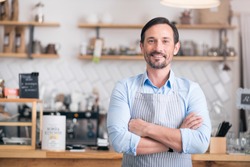 Own business. Successful cheerful small business owner standing with crossed arms