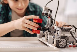 Inventive teen kid constructing robot in the studio