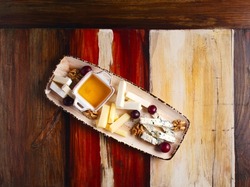 Cheese plate. Assorted cheese with walnuts, grapes and honey on a ceramic rectangular plate on a wooden texture background. Top view from space. Snack theme. Appetizer for wine, alcoholic beverages.