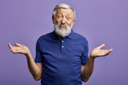 bearded old man expresses clueless with raised arms looking at the camera.isolated blue background. it doesn't bother me. it doesn't care me.I don't know. I don't have an idea. studio shot.