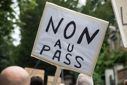 people protesting in the street against the sanitary pass, with banner in french, non au pass, in english , no pass 