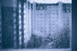 rainy droplets on a blue window glass transparent surface. drops on window shield in a rainy days  in night city. stormy weather. isolation sad depression concept.  rainy season. stay home.