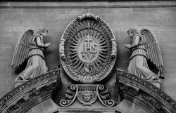 Black and white abstract photograph of sculptures of angels and doves above the entrance to the temple.