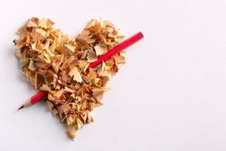The heart of pencil shavings is pierced with a red pencil like an arrow. Valentine's Day.