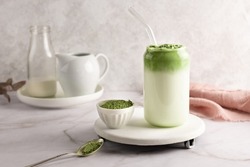 Whipped grean tea with milk, dalgona matcha latte in glass with matcha powder on white background.
