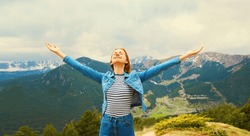 Travel concept, happy woman enjoying fresh air mountains raising her hands up on Andorra mountain background