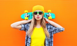 Fashion pretty cool girl with skateboard over colorful orange background