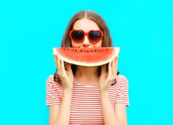 portrait happy young woman is holding slice of watermelon over colorful blue background