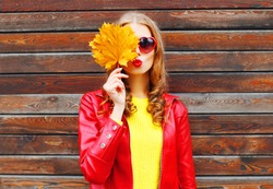 pretty woman with autumn yellow maple leaves over wooden background