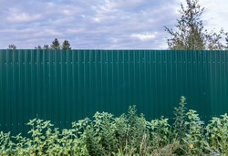Profiled metal fence. sheet metal. Fencing of a house, structure. Metal gates. Territory protection. Day. Autumn. Russia.