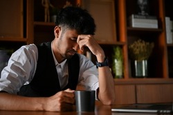 Tired and stressed asian businessman or male CEO in the office, upset and worried about his company business turnover.