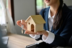 cropped image, Beautiful and expert Asian female real estate agent holding a house model and house key. Real estate investment concept